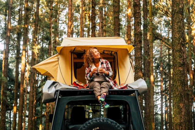 Woman sitting on roof of car tent