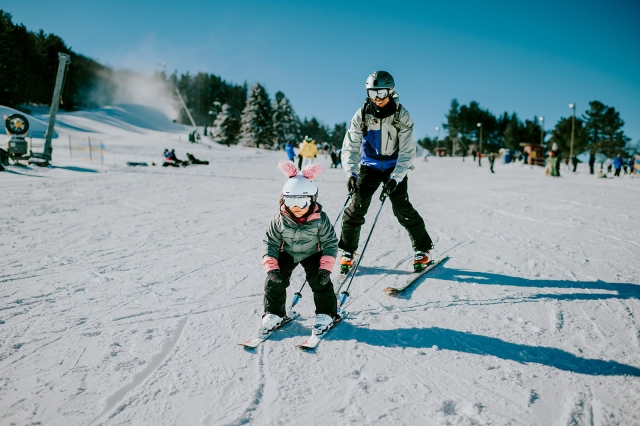Dad teaching child to ski