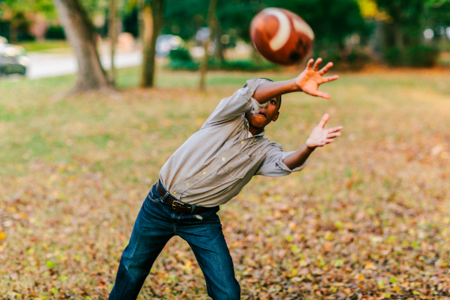 Young boy catching a football in the autumn leaves