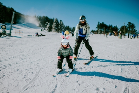 Dad teaching child to ski