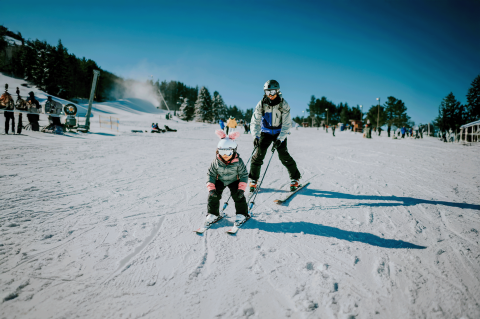 Dad teaching young daughter to ski